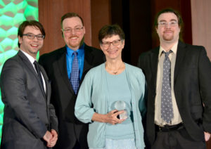 Picture of 3 men and one women with award in her hands